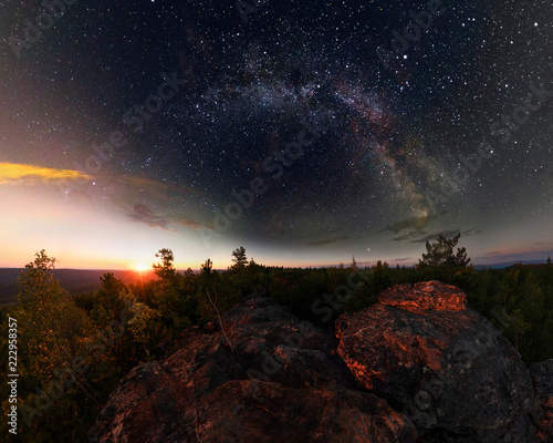 Dawn in the forest under the starry sky a milky way. Panorama.