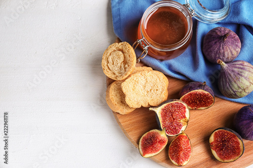 Fresh ripe figs with jar of honey and bread on wooden board