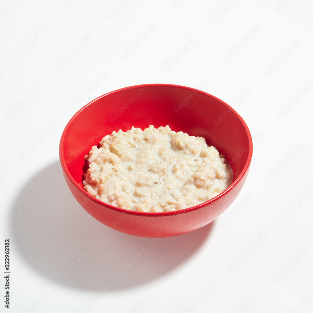Oatmeal Porridge with Milk in Red Bowl Isolated on White Background Oatmeal Porridge with Milk in Red Bowl Isolated on White Background