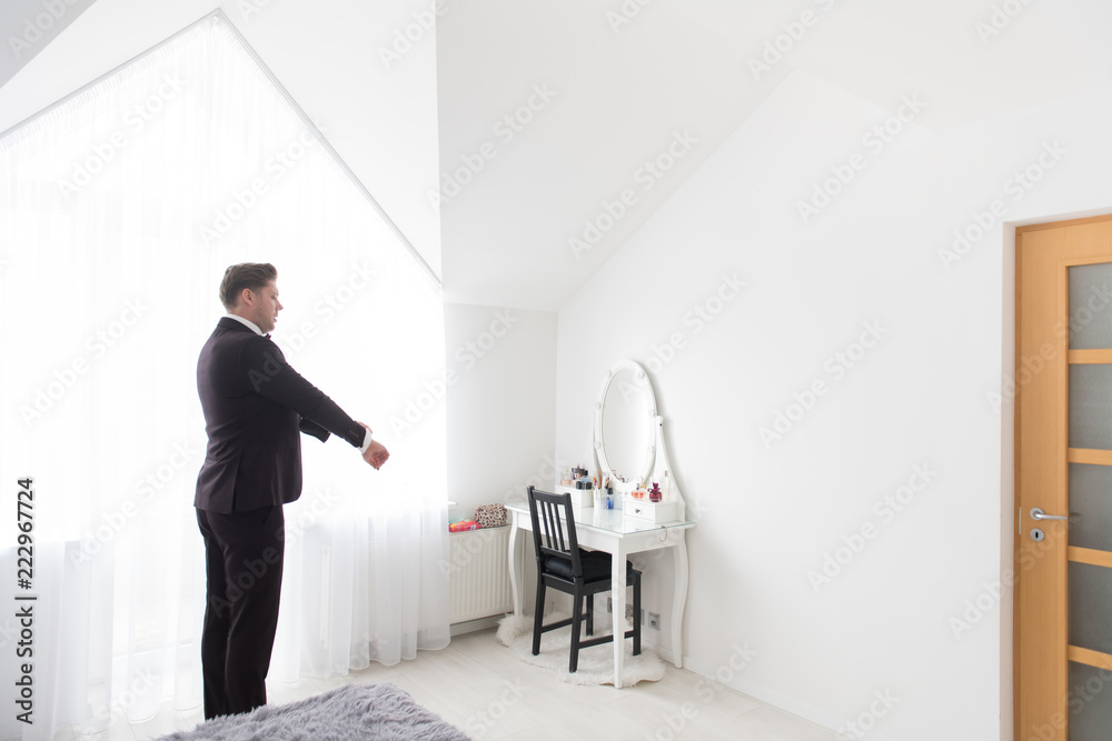 Young man putting on costume in room Young man putting on costume in room