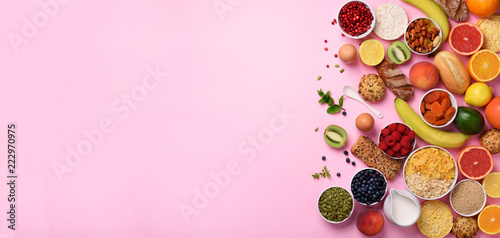 Organic food frame. Banner. Healthy breakfast ingredients. Oat and corn flakes, eggs, nuts, fruits, berries, toast, milk, yogurt, orange, banana, peach on pink background. Top view, copy space photo