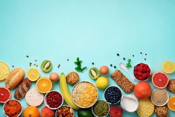 Healthy breakfast ingredients, food frame. Oat and corn flakes, eggs, nuts, fruits, berries, toast, milk, yogurt, orange, banana, peach on blue background. Top view, copy space. Flat lay