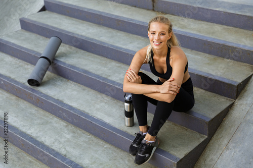 Amazing young sports woman sitting on steps outdoors. © Drobot Dean
