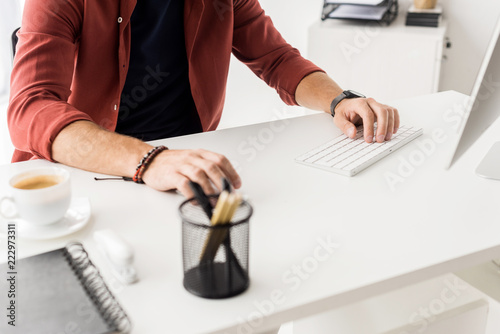 cropped view of businessman sitting by table in modern office