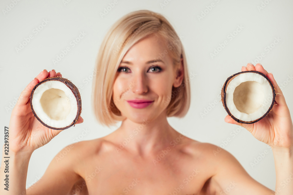 Beautiful young blonde hairstyle girl with a long eyelashes make-up and perfect skin with coconut in her hand in the studio on a white background. Beauty face hair care. Beautiful young blonde hairstyle girl with a long eyelashes make-up and perfect skin with coconut in her hand in the studio on a white background. Beauty face hair care.