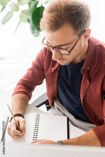 casual businessman in glasses writing in notebook