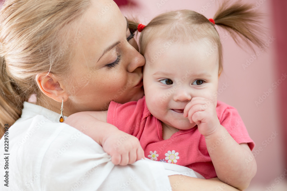 Portrait of happy mother kissing her baby daughter at home Portrait of happy mother kissing her baby daughter at home