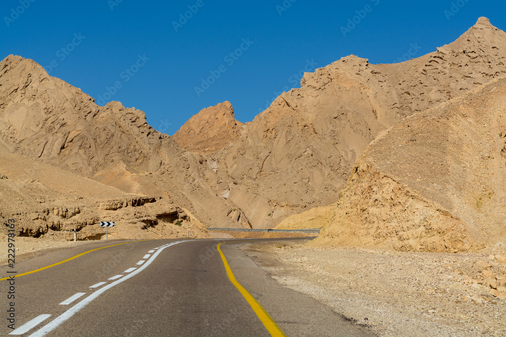 Asphalt road in desert Negev, Israel, road 12, transport infrastructure in desert, scenic mountains route from Eilat to north of Israel Asphalt road in desert Negev, Israel, road 12, transport infrastructure in desert, scenic mountains route from Eilat to north of Israel