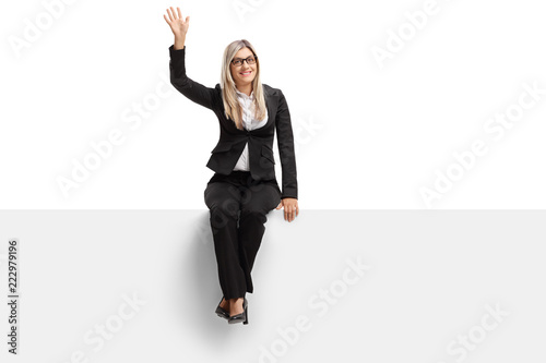 Businesswoman seated on a panel waving
