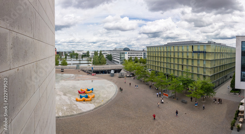 Blick von oben auf den Willy-Brandt-Platz in der Münchener Messestadt mit de rMesse München und dem Messesee im Hintergrund