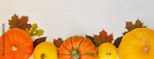 Yellow and orange pumpkins and autumn leaves on white wooden background for harvest fall and thanksgiving theme.