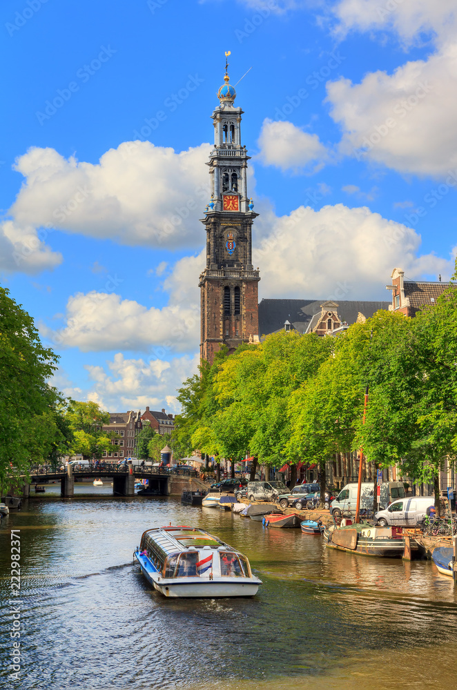 Fototapeta premium Wycieczka statkiem po kanale Prinsengracht, wpisanym na listę światowego dziedzictwa UNESCO, z Westerkerk (kościół zachodni) w słoneczny letni dzień z błękitnym niebem i chmurami