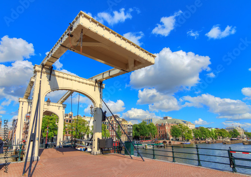 Beautiful close up wide angle of the skinny bridge  magere brug  over the river Amstel in Amsterdam  the Netherlands  on a sunny summer day with blue sky and some clouds  