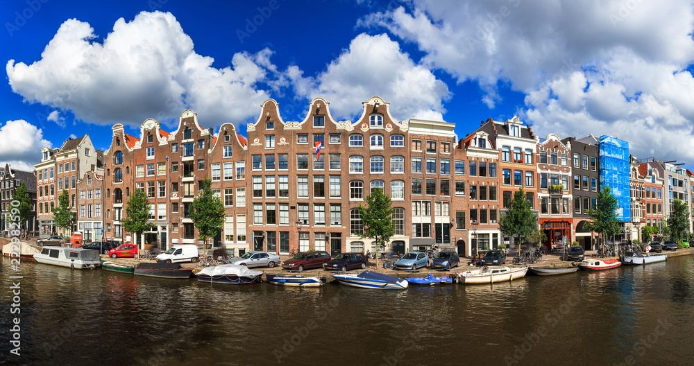 Beautiful panoramic linear panorama of the UNESCO world heritage Prinsengracht canal in Amsterdam, the Netherlands, on a sunny summer day with a blue sky and clouds
