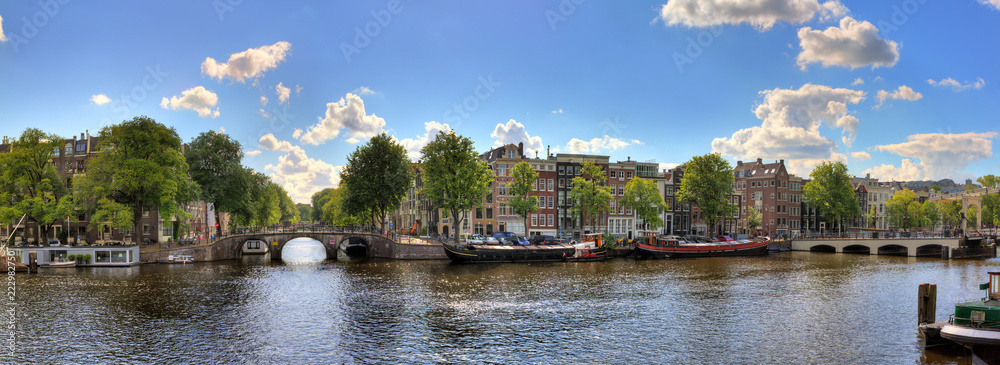 Beautiful panoramic panorama of the river Amstel in Amsterdam, the Netherlands, on a sunny summer day with some clouds