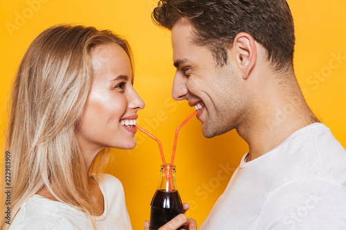 Pretty young couple standing isolated over yellow