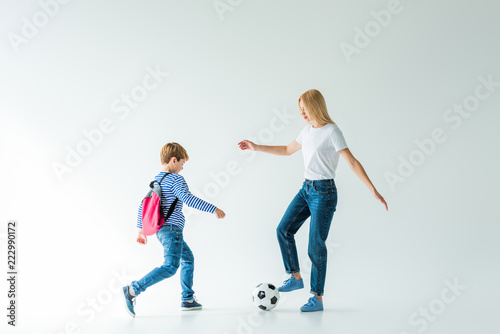 mother and son with backpack playing football on white