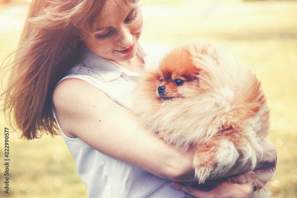 young smiling woman with blonde hair and her cute Pomeranian dog having great time together