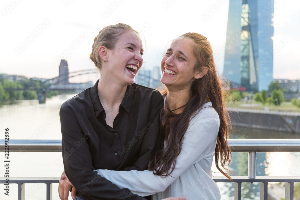 Girlfriends Embracing and Laughing Wildly on City Bridge Over River 2