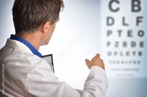 Ophthalmologist on his back showing a board of letters