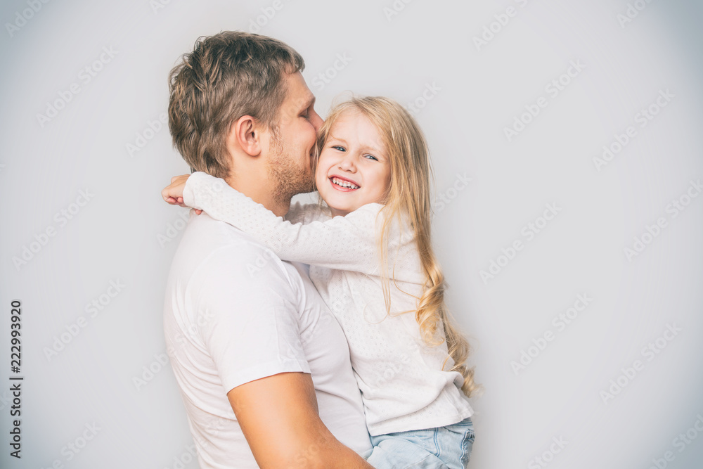Father with a little daughter in his arms laughing happy and playing on a gray background in the Studio Father with a little daughter in his arms laughing happy and playing on a gray background in the Studio