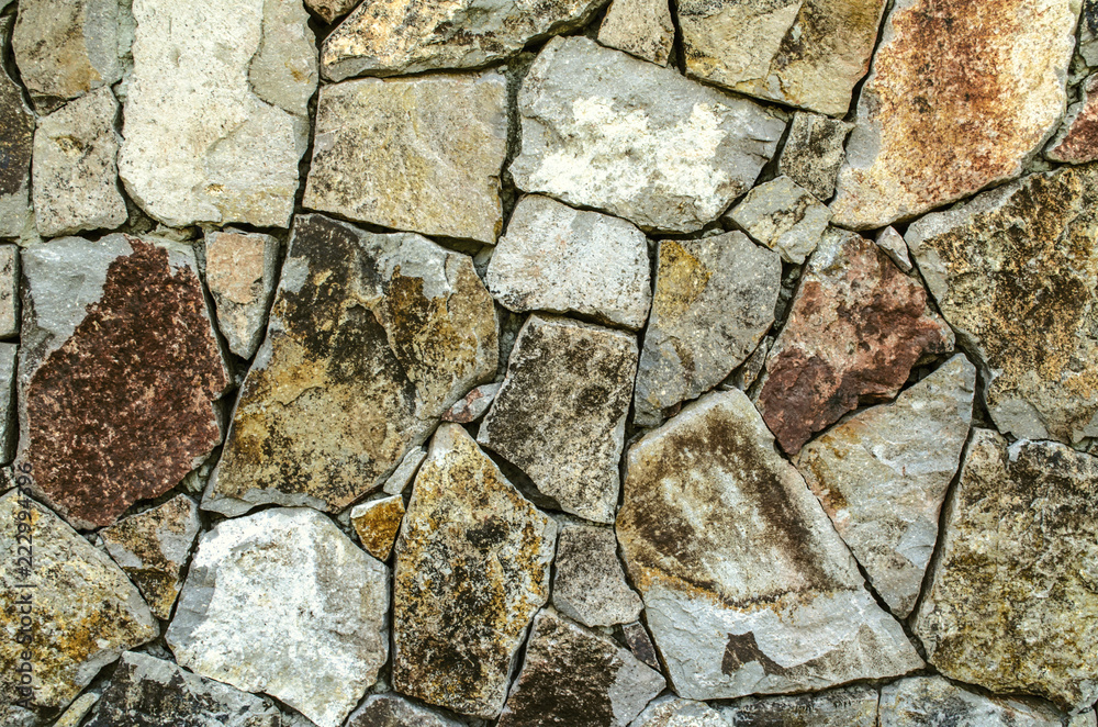 Fototapeta premium Color background of raw natural stone, for the facade of the house in gray and brown shades 