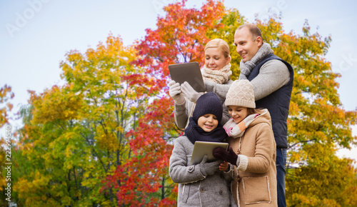 family, technology and season concept - happy mother, father, daughter and son with tablet pc computers over autumn park background