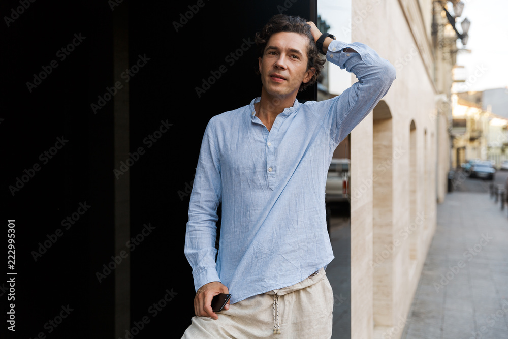 Confident young casual man holding mobile phone Confident young casual man holding mobile phone