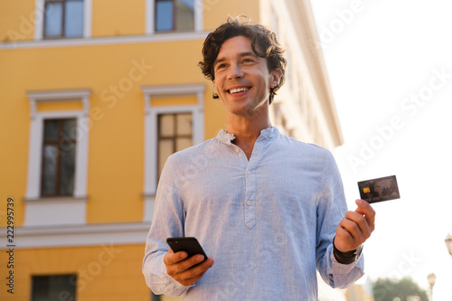 Cheerful young casual man holding mobile phone photo