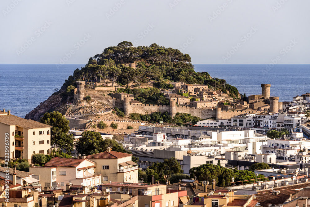 Spain, Catalonia, Costa Brava, Tossa de Mar: Panoramic view with famous fortified old town, mediterranean sea, skyline, cityscape, green trees and blue sky in the background - travel.