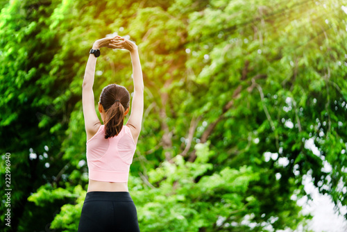 Female athlete standing arms in park. It is a warm up before the activity, because it will not muscle cause inflammation. Or cramping While running or playing sports