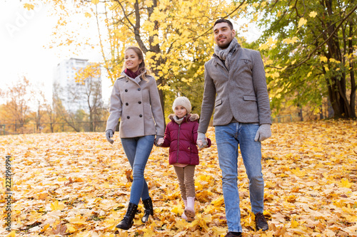family, season and people concept - happy mother, father and little daughter walking at autumn park