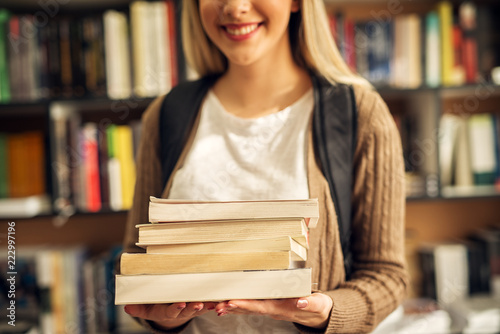 Close up of a female student hands full of books.