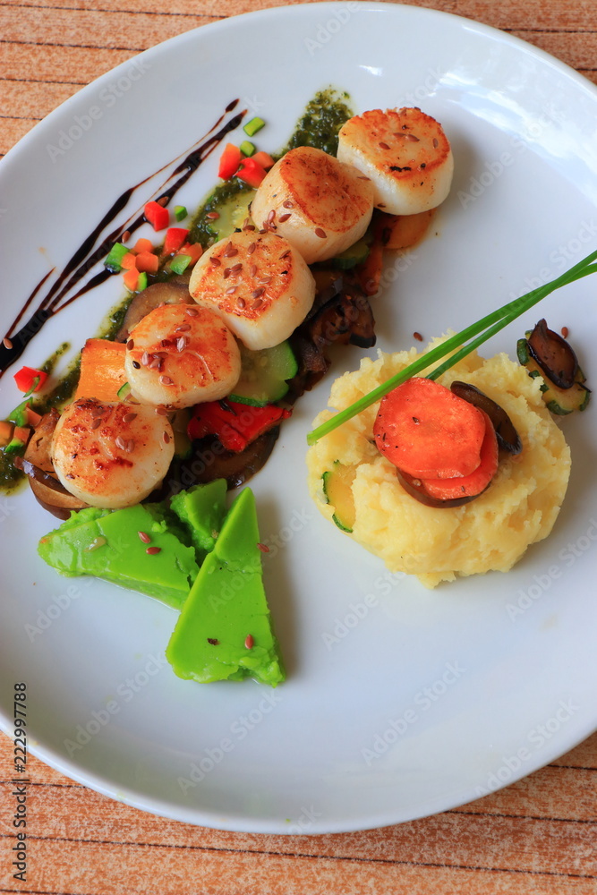 Plate of scallops cooked with its vegetables garnish in a french gastronomic restaurant
