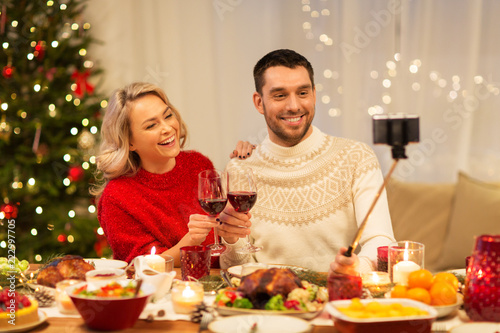 christmas  holidays  technology and people concept - happy couple in taking selfie by smartphone at home dinner