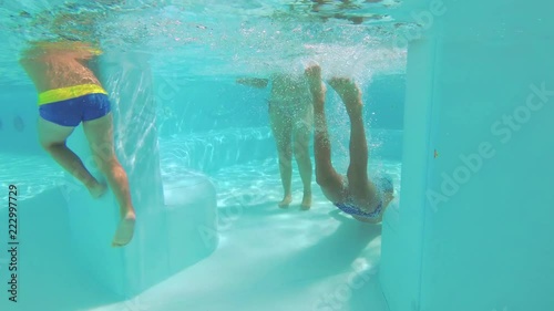 The teenager swims in the pool under the water.