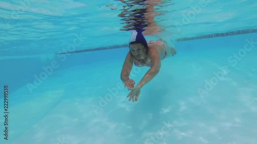 The teenager swims in the pool under the water.
