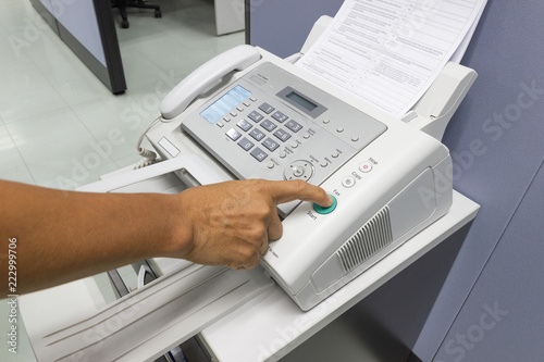 Finger pressing start button on the fax, business concept.