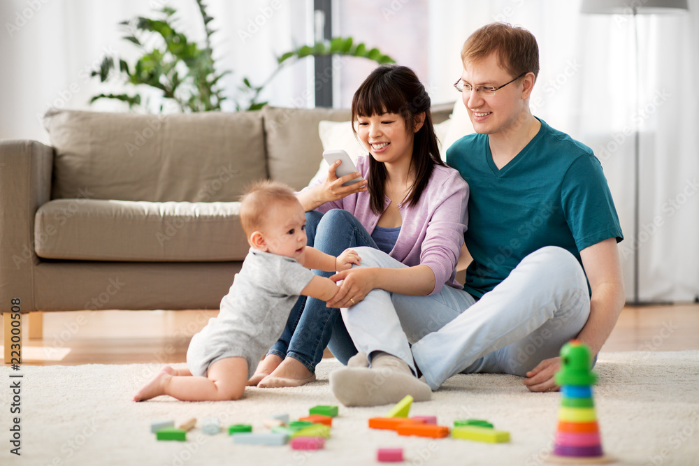 family, technology and people concept - happy mother and father taking picture or recording video of baby boy with smartphone at home family, technology and people concept - happy mother and father taking picture or recording video of baby boy with smartphone at home