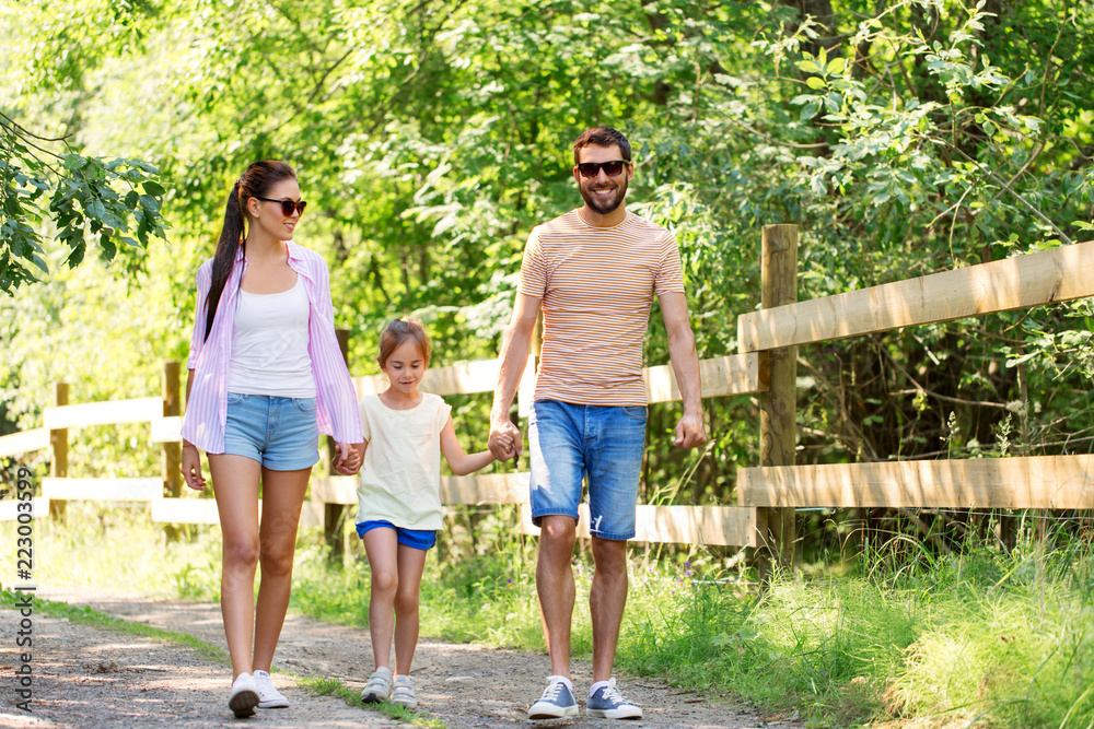 family, leisure and people concept - happy mother, father and little daughter walking in summer park