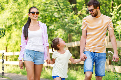family, leisure and people concept - happy mother, father and little daughter walking in summer park © Syda Productions