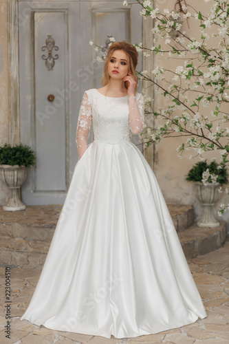 Portrait of charming woman in wedding dress. Posing on the background walls with classic moldings