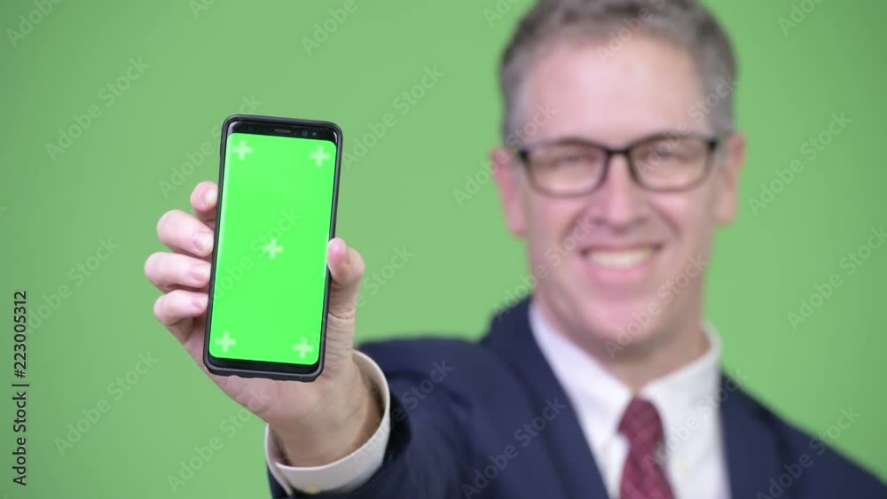 Studio shot of happy mature businessman showing phone Studio shot of happy mature businessman showing phone