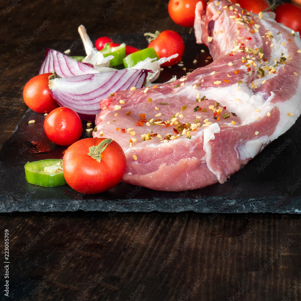 Raw meat, salt, pepper, tomato, spices, garlic, rustic wood background Raw meat, salt, pepper, tomato, spices, garlic, rustic wood background