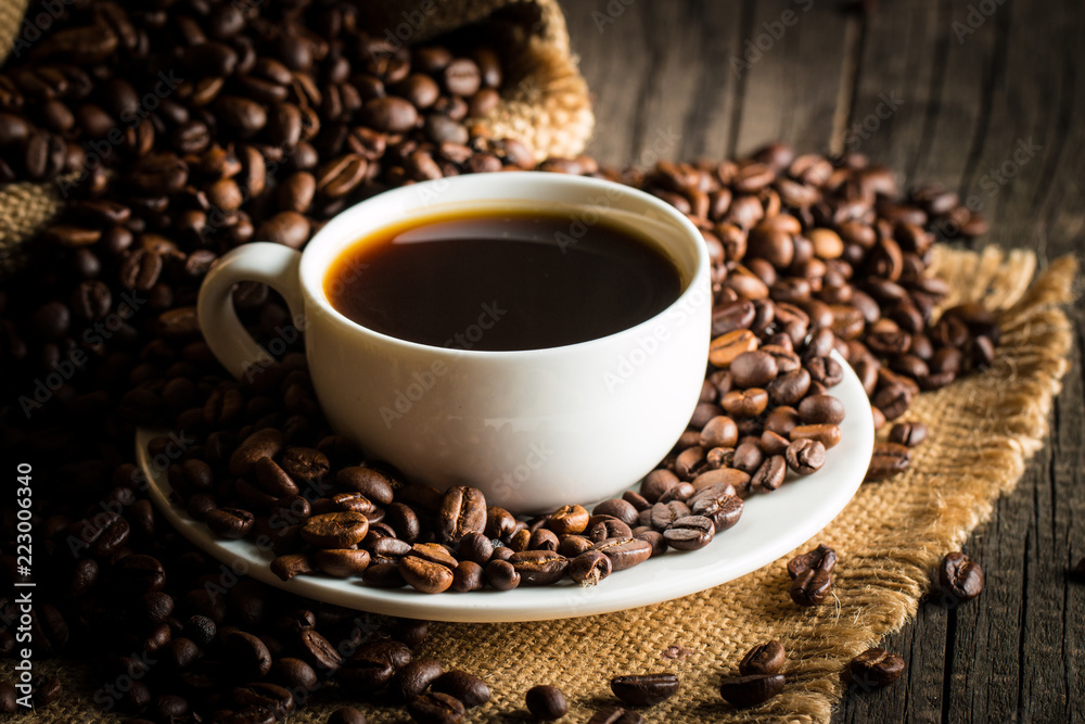 Coffee cup and beans on a rustic background. Coffee Espresso and a piece of cake with a curl. Cup of Coffee and coffee beans on table. Coffee cup and beans on a rustic background. Coffee Espresso and a piece of cake with a curl. Cup of Coffee and coffee beans on table.