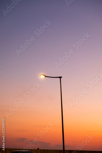 silhouette of a lonely standing pillar with a lantern standing on the background of the sunset sky blue with red