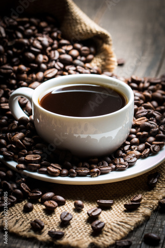 Coffee cup and beans on a rustic background. Coffee Espresso and a piece of cake with a curl. Cup of Coffee and coffee beans on table.