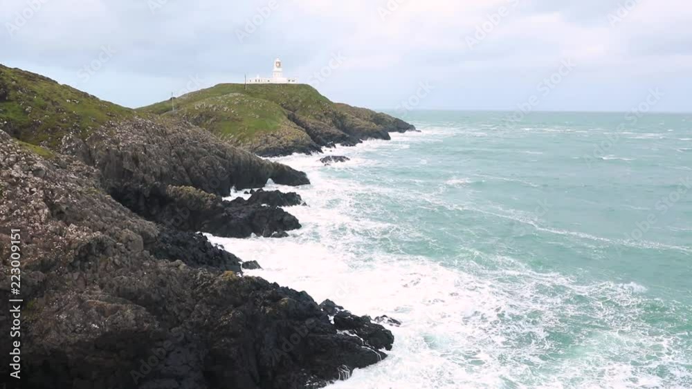 Moody seascape with lighthouse on the cliffs and big waves Moody seascape with lighthouse on the cliffs and big waves