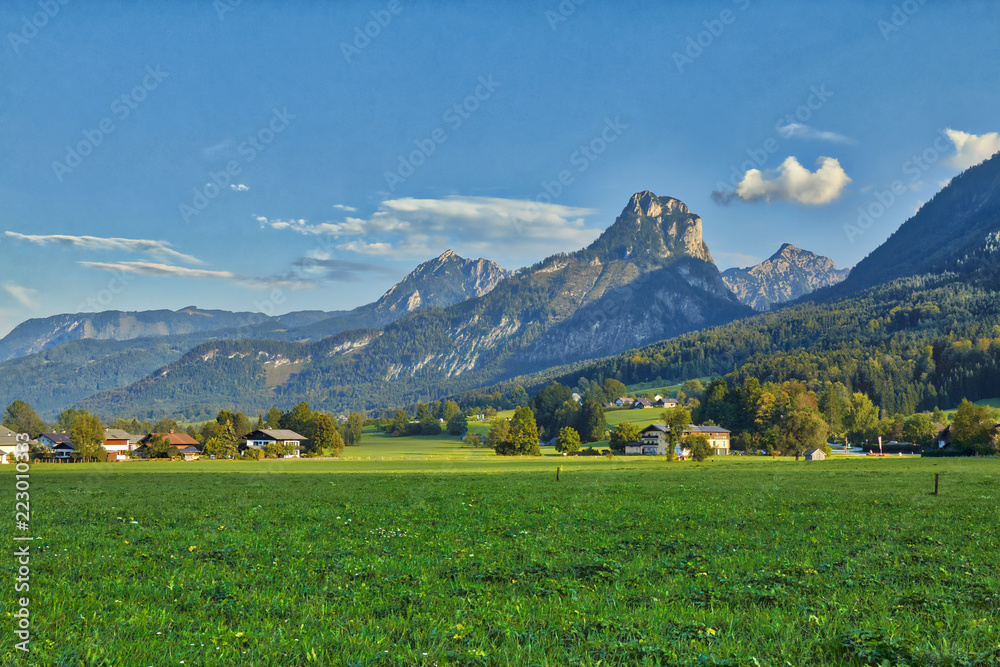 Obraz premium HDR beautiful landscape with lush green grass land and Alpine mountains near Wolfgangsee lake in Austria.