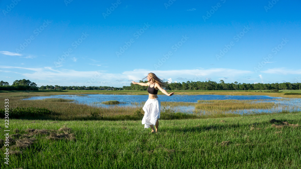 Beautiful young spiritual blonde woman long hair dancing and spinning in a  field next to a lake white skirt Stock Photo | Adobe Stock
